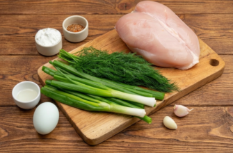 Набор продуктов для ПП-котлет: куриная грудка, зеленый лук, укроп, яйцо, чеснок и специи на доске